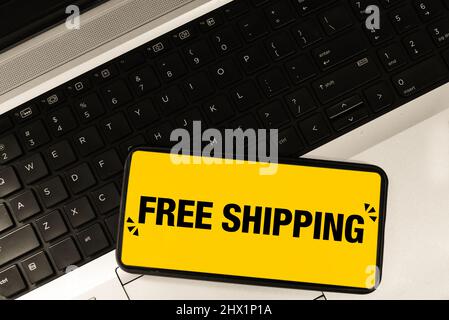 Kostenloser Versand auf mobilen Bildschirm mit Laptop-Tastatur Hintergrund. Moderner eCommerce und bietet einen konzeptionellen Hintergrund Stockfoto