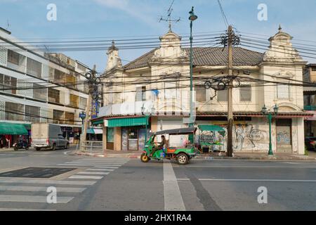 Ein Tuk-Tuk (Dreirad-Taxi) passiert ein malerisches altes Gebäude in der Atsadang Rd. Im historischen Stadtgebiet von Phra Nakhon, Bangkok, Thailand Stockfoto