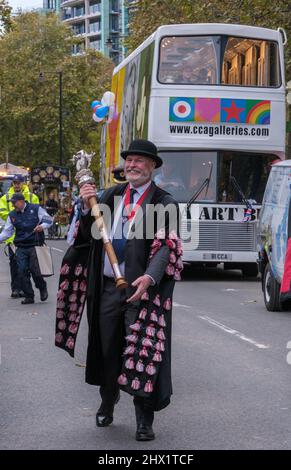 Lächelnder Mann in zeremonieller Robe mit einem Zepter geht vor den CAA Art Bus auf der Lord Mayor’s Show 2021, Victoria Embankment, London. Stockfoto