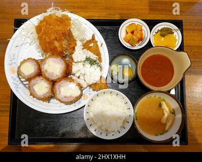 Cheese Katsu, ein japanisches paniertes, frittiertes Schweinefleisch gefüllt mit Käse. Serviert mit Kohlsalat, Wasabi, Kimchi, Miso-Suppe und Reis. Stockfoto