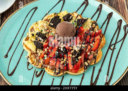 Herzwaffel mit Ananas und Erdbeere mit Gummy Candy und Eis darauf. Stockfoto