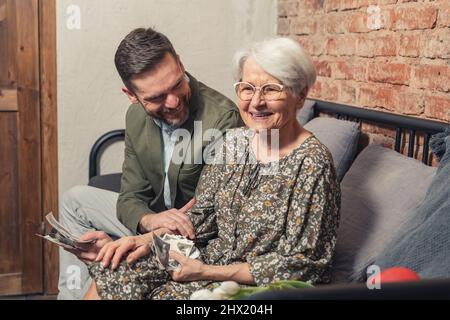 Fröhliche Familie feiert den Muttertag Großelterntag mit Blick auf alte Schwarz-Weiß-Fotografien . Hochwertige Fotos Stockfoto