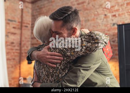 kaukasischer Tausendjährige Unternehmer Mann glücklich umarmt seine pensionierte grauhaarige Großmutter . Hochwertige Fotos Stockfoto