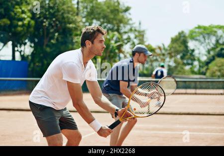 Doppelte Probleme. Schuss von zwei Tennisspielern auf der gleichen Mannschaft, die auf den Ball warten. Stockfoto