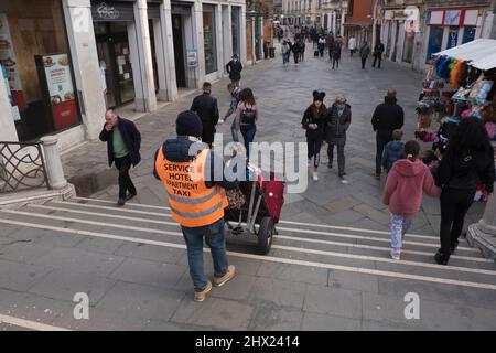 Einer der schwierigsten Jobs in Venedig, ein Hotel Porter, das das Gepäck der Gäste über die vielen Fußgängerbrücken transportiert Stockfoto