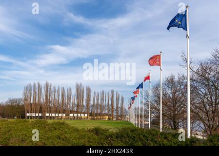 Masten mit Flaggen Polens und der Europäischen Union. Inschrift: Nigdy wiecej wojny (auf Englisch: No more war) im Hintergrund. Danzig Westerplatte, Polen Stockfoto