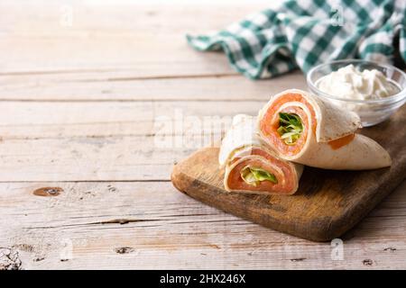 Lachs wickeln Sandwich-Rolle mit Käse und Gemüse auf Holztisch Stockfoto