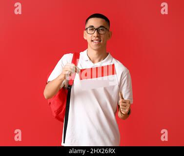 Junger asiatischer Mann in Brillen mit indonesischer Flagge auf rotem Hintergrund Stockfoto