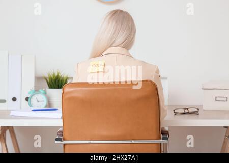 Reife Frau mit klebrigem Papier auf ihrem Rücken im Büro. April Narren Tag Feier Stockfoto