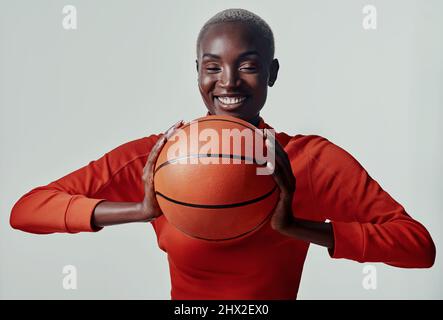 Lust auf ein paar Reifen. Studioaufnahme einer attraktiven jungen Frau, die vor grauem Hintergrund Basketball spielt. Stockfoto