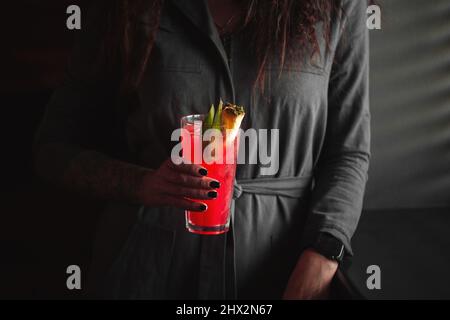 Frau hält roten Cocktail in einem Highball mit Eis Stockfoto