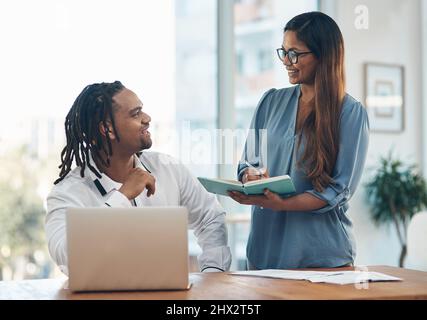 Notieren ihrer großen neuen Pläne. Aufnahme von zwei Geschäftsleuten, die in einem Büro eine Diskussion führen. Stockfoto