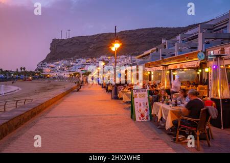 Blick auf Cafés und Restaurants in Puerto de Mogan in der Abenddämmerung, Playa de Puerto Rico, Gran Canaria, Kanarische Inseln, Spanien, Europa Stockfoto