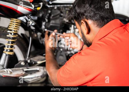 Schulteraufnahme des Fokus auf Mechaniker, Motorrad-Mechaniker Befestigung oder Reparatur Motor des Motorrads in der Garage mit Kopieplatz - Konzept der harten Arbeit Stockfoto