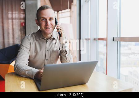 Ein erfolgreicher Geschäftsmann sitzt in einem funktionierenden Café und arbeitet an einem wichtigen Projekt. Geschäftsmann tippt auf einem Laptop. Geschäftsmann mit Laptop im Café Stockfoto