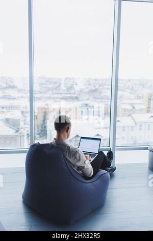 Konzentrierter junger Geschäftsmann, der auf den Laptop-Bildschirm schaut, Informationen online oder im Home Office Remote online arbeitet und per CLI kommuniziert Stockfoto