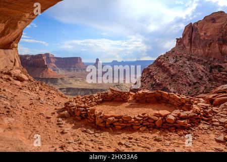 Die False Kiva Ruine in einer Nische im Canyonlands National Park in der Nähe von Moab, Utah. In der Ferne befindet sich der Candlestick Tower, ein Sandstein-Monolith von Wing Stockfoto