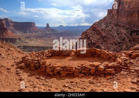 Die False Kiva Ruine in einer Nische im Canyonlands National Park in der Nähe von Moab, Utah. In der Ferne befindet sich der Candlestick Tower, ein Sandstein-Monolith von Wing Stockfoto