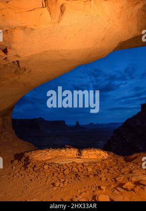 Die False Kiva Ruine bei Nacht im Canyonlands National Park, Moab, Utah. In der Ferne befindet sich der Candlestick Tower, ein Sandsteinmonolith aus Wingate Sand Stockfoto