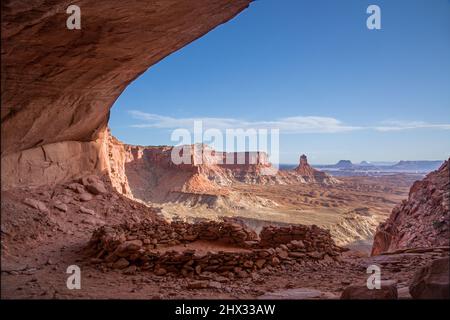 Die False Kiva Ruine in einer Nische im Canyonlands National Park in der Nähe von Moab, Utah. In der Ferne befindet sich der Candlestick Tower, ein Sandstein-Monolith von Wing Stockfoto