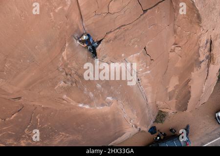 Eine Bleibergsteigerin legt einen Seilanker an der Spitze der Flocken of Wrath, Wall Street in der Nähe von Moab, Utah, auf. Stockfoto