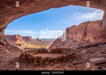 Die False Kiva Ruine in einer Nische im Canyonlands National Park in der Nähe von Moab, Utah. In der Ferne befindet sich der Candlestick Tower, ein Sandstein-Monolith von Wing Stockfoto