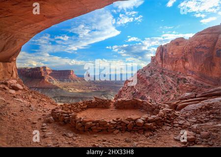 Die False Kiva Ruine in einer Nische im Canyonlands National Park in der Nähe von Moab, Utah. In der Ferne befindet sich der Candlestick Tower, ein Sandstein-Monolith von Wing Stockfoto