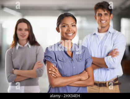 Gute Führung macht Erfolg leicht. Ein junges Geschäftsteam, das mit gefalteten Armen steht. Stockfoto