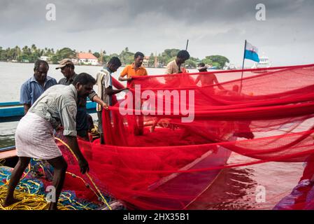 Fischer neigen zu ihren Fischerbooten und Netzen. Fotografiert in Kerala, Indien Stockfoto