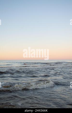 Seascape bei Sonnenuntergang. Minimalistischer Blick auf das kalte Meer bei Sonnenuntergang. Klarer Himmel, Horizont über dem Wasser Stockfoto