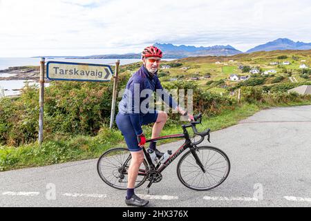 Ein Radfahrer im Dorf Tarskavaig in der Tarskavaig Bay auf dem Sleat Penisula im Süden der Isle of Skye, Highland, Schottland, Großbritannien. Die Cuillins A Stockfoto