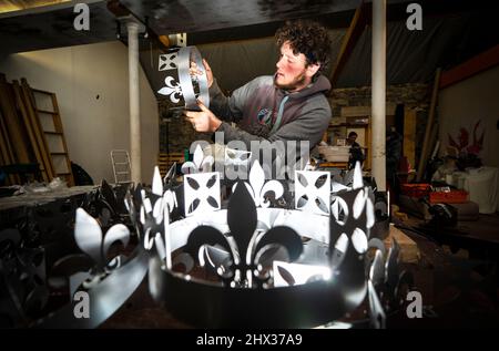 Lewis Wilde inspiziert den Kronenabschnitt eines der gasbetriebenen Leuchttürme, die er hergestellt hat und mit denen der Beginn des Platin-Jubiläums von Königin Elizabeth II. Im Juni auf der Fountain Designs-Werkstatt in Selkirk, in den Scottish Borders, signalisiert werden soll. Inspiriert von den Kronjuwelen, die bei der Krönung 1953 verwendet wurden, werden die Leuchttürme zu den Tausenden gehören, die von Gemeinden, Wohltätigkeitsorganisationen und anderen Gruppen im ganzen Land und in den überseeischen Gebieten beim ersten Gemeinschaftsereignis des viertägigen Jubiläumswochenendes im Juni beleuchtet werden. Bilddatum: Mittwoch, 9. März 2022. Stockfoto