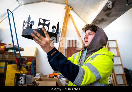 Lewis Wilde inspiziert den Kronenabschnitt eines der gasbetriebenen Leuchttürme, die er hergestellt hat und mit denen der Beginn des Platin-Jubiläums von Königin Elizabeth II. Im Juni auf der Fountain Designs-Werkstatt in Selkirk, in den Scottish Borders, signalisiert werden soll. Inspiriert von den Kronjuwelen, die bei der Krönung 1953 verwendet wurden, werden die Leuchttürme zu den Tausenden gehören, die von Gemeinden, Wohltätigkeitsorganisationen und anderen Gruppen im ganzen Land und in den überseeischen Gebieten beim ersten Gemeinschaftsereignis des viertägigen Jubiläumswochenendes im Juni beleuchtet werden. Bilddatum: Mittwoch, 9. März 2022. Stockfoto