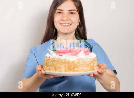 Der Arzt oder die Krankenschwester hält einen großen Geburtstagskuchen, herzlichen Glückwunsch zum Tag des Arztes oder der Krankenschwester Stockfoto