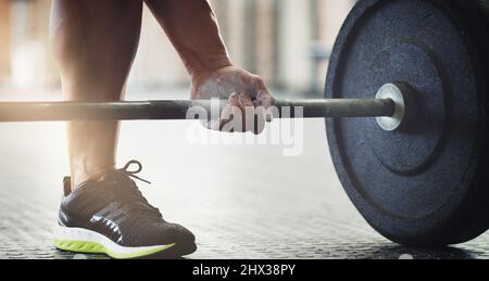 Heben Sie mit den Beinen. Eine kurze Aufnahme eines unerkennbaren jungen Mannes, der im Fitnessstudio Gewichte hebt. Stockfoto