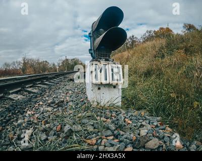 Signalgeber oder Ampelsignal auf der Bahn. Kurve der Eisenbahnstrecke. Eisenstangen auf dem Land. Stockfoto