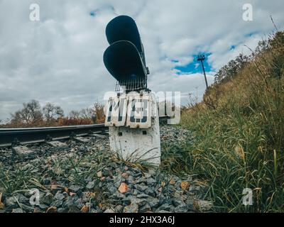 Signalgeber oder Ampelsignal auf der Bahn. Kurve der Eisenbahnstrecke. Eisenstangen auf dem Land. Stockfoto