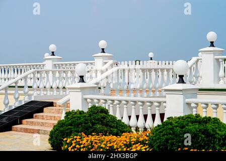 Balkon mit weißen Säulen, runden Lampen und Steintreppe. Stockfoto