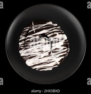 Brötchen mit Schokolade bedeckt, auf einem dunklen Teller auf schwarzem Hintergrund Stockfoto