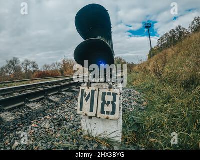 Signalgeber oder Ampelsignal auf der Bahn. Kurve der Eisenbahnstrecke. Eisenstangen auf dem Land. Stockfoto