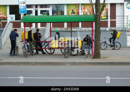 KIEW, Ukraine - 19. April ,2020: Glovo Couriers. Kuriere warten während der Krise an einer Bushaltestelle auf eine Bestellung und in Kiew in Quarantäne Stockfoto