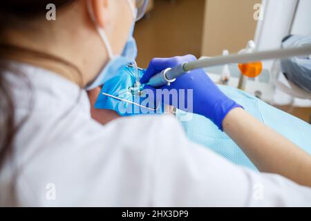 Ein Zahnarzt behandelt einen männlichen Patienten mit zahnmedizinischen Instrumenten. Der Zahnarzt untersucht die Zähne der Patienten in der Zahnklinik. Selektiver Fokus Stockfoto