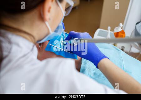 Ein Zahnarzt behandelt einen männlichen Patienten mit zahnmedizinischen Instrumenten. Der Zahnarzt untersucht die Zähne der Patienten in der Zahnklinik. Selektiver Fokus Stockfoto