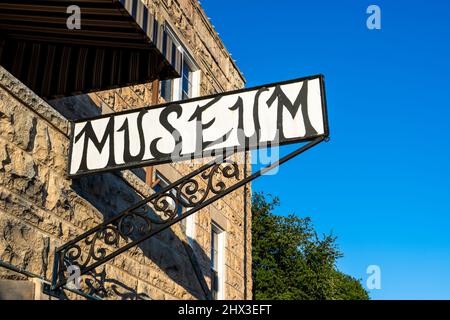 Altes Schriftwort Museum auf einem Schild mit schwarzem Text auf weißem Hintergrund und schmiedeeisernem Halter Stockfoto