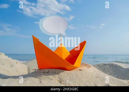 Orange Papier Boot auf Sandy Seashore Nahaufnahme kleines Boot aus Papier auf dem Hintergrund Stockfoto