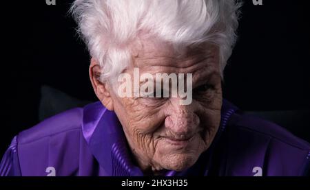 Porträt einer ernsthaften älteren Frau vor schwarzem Hintergrund Stockfoto