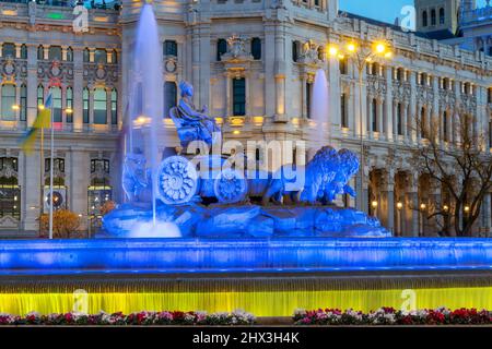 Cibeles-Brunnen in Madrid, Spanien, blau und gelb beleuchtet mit einer Flagge der Ukraine Stockfoto