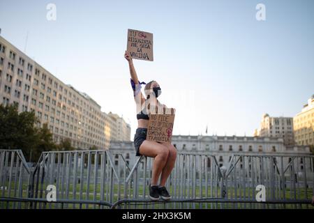 Santiago, Chile. 08. März 2022. Eine Aktivistin hält während der Demonstration Plakate vor dem Regierungspalast La Moneda hoch. Feministinnen marschieren am 8.. März in Santiago de Chile zu einer Demonstration, die an die sozialen, politischen und wirtschaftlichen Errungenschaften von Frauen erinnert. (Foto von Vanessa Rubilar/SOPA Images/Sipa USA) Quelle: SIPA USA/Alamy Live News Stockfoto