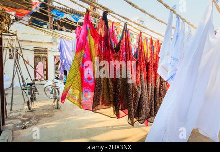 Bunte Saris und weiße Laken hängen zum Trocknen aus und trocknen in der Sonne im Mahalaxmi Dhobi Ghat, einem großen Open-Air-Waschsalon in Mumbai, Indien Stockfoto