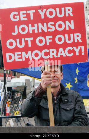 London, England. 9.. März 2022. Ein Mann, der ein Banner mit der Aufschrift ‘Get Your Johnson Out of Democracy’ hält. Anti-Tory-Aktivisten vor dem Parlament protestieren gegen die konservative Regierung und den britischen Premierminister Boris Johnsons, die am Brexit beteiligt sind. Kredit: SMP Nachrichten / Alamy Live Nachrichten Stockfoto